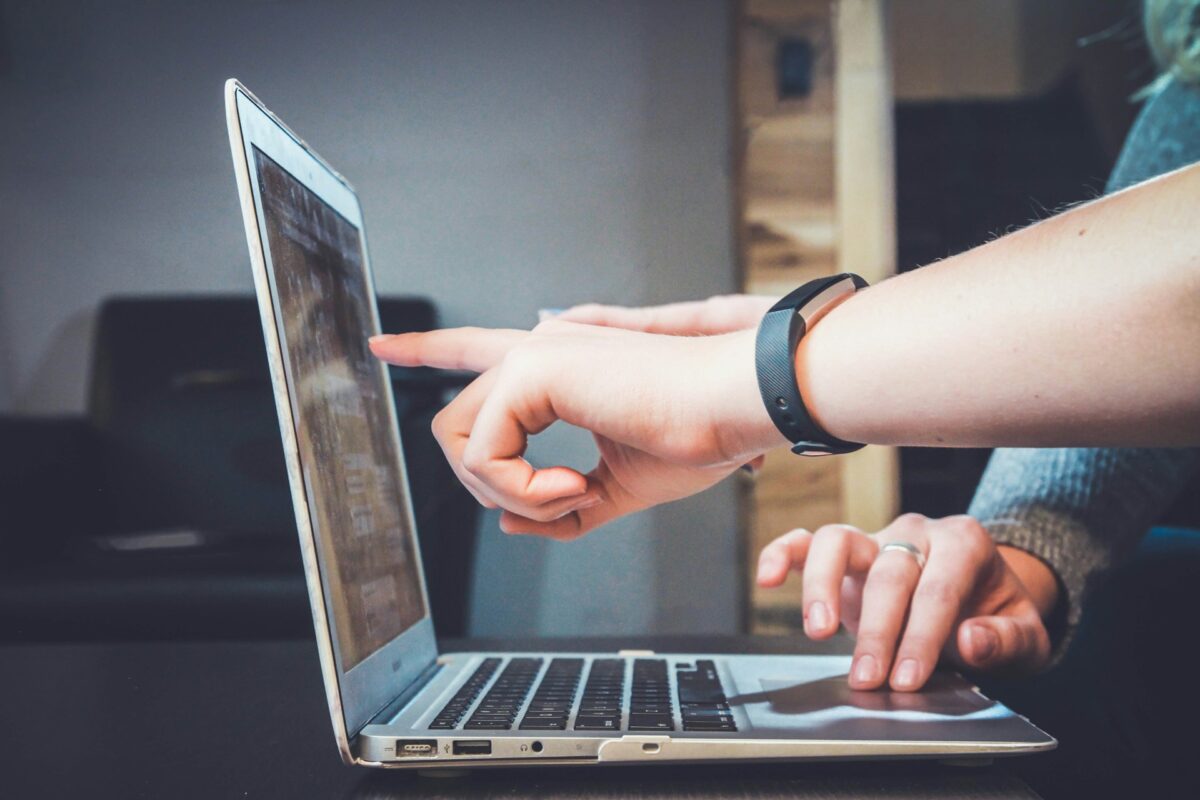 Duas pessoas usando um notebook; uma aponta para a tela enquanto a outra digita, sugerindo colaboração na análise de documentos digitais