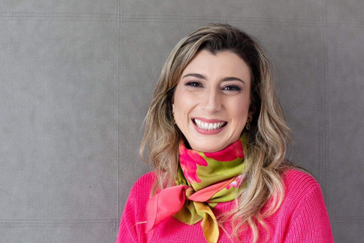 Architect and urban planner Eleonora Zioni, renowned in the field of hospital architecture, pictured against a gray background, smiling