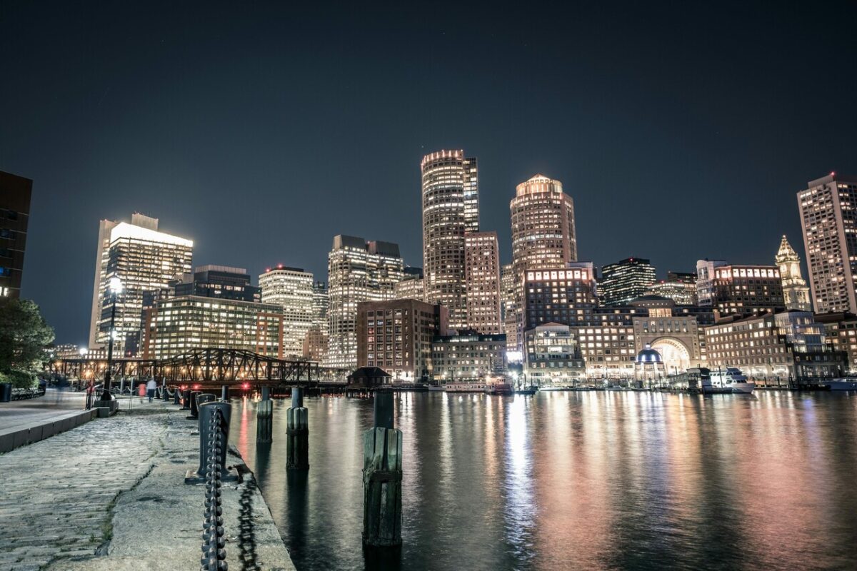 View of the Boston, Massachusetts, waterfront at night, with illuminated buildings reflected in the water. The image shows the skyline of the city, which is home to important scientific research centers and educational institutions.