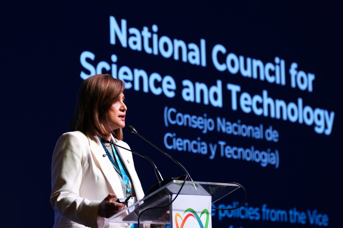 Karin Herrera, vice president of Guatemala, speaks at a podium during an international event, in front of a large screen displaying the words “National Council for Science and Technology”
