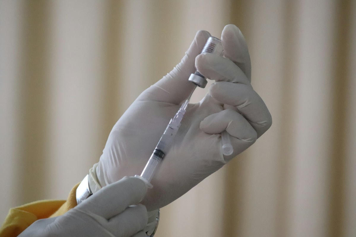 A healthcare professional prepares a syringe with a vaccine or injectable medication dose, in an image that evokes immunization and healthcare.