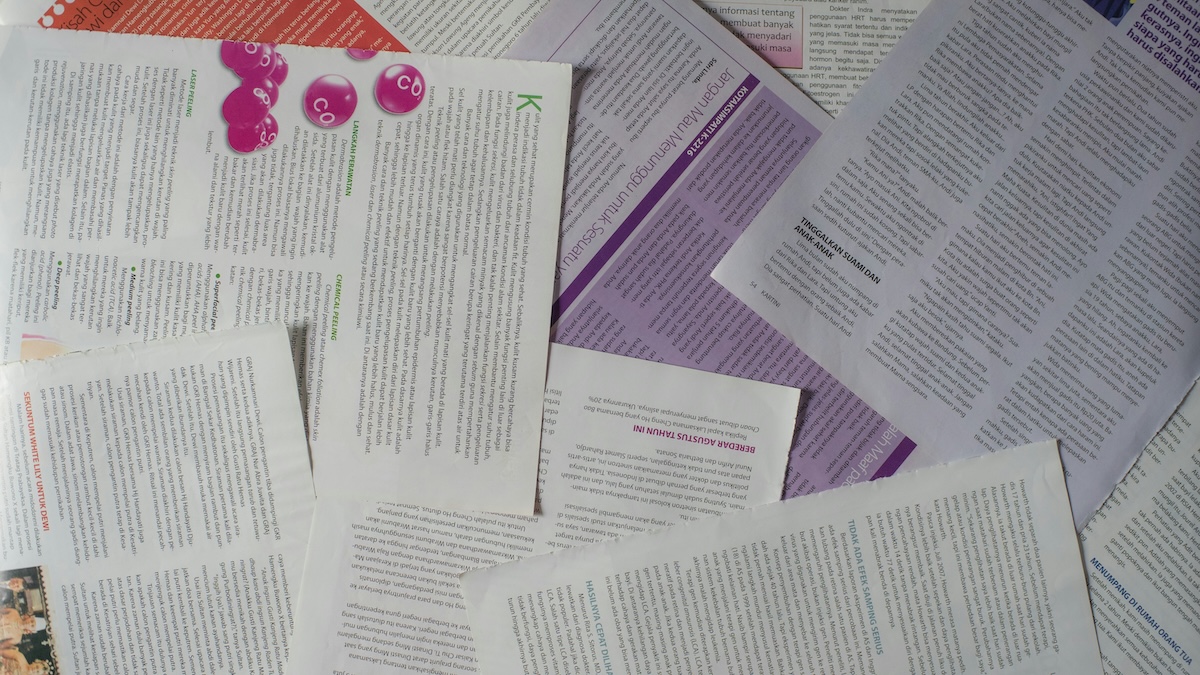 The image shows an overhead view of printed scientific pages overlapping eachother haphazardly on a flat surface. In the center, a text box on one page is highlighted in purple.